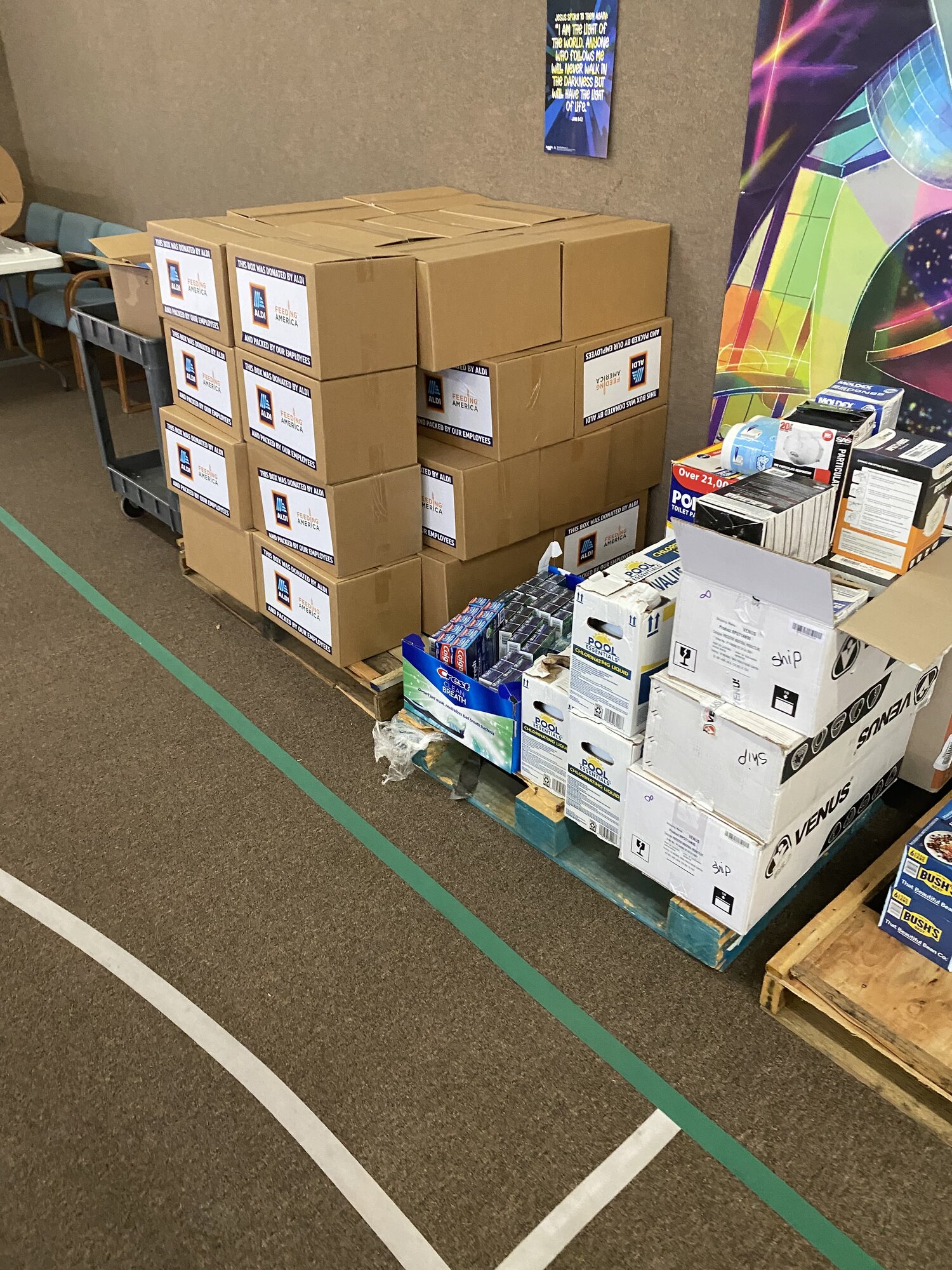 Boxes of donated supplies stacked on pallets in the church gymnasium