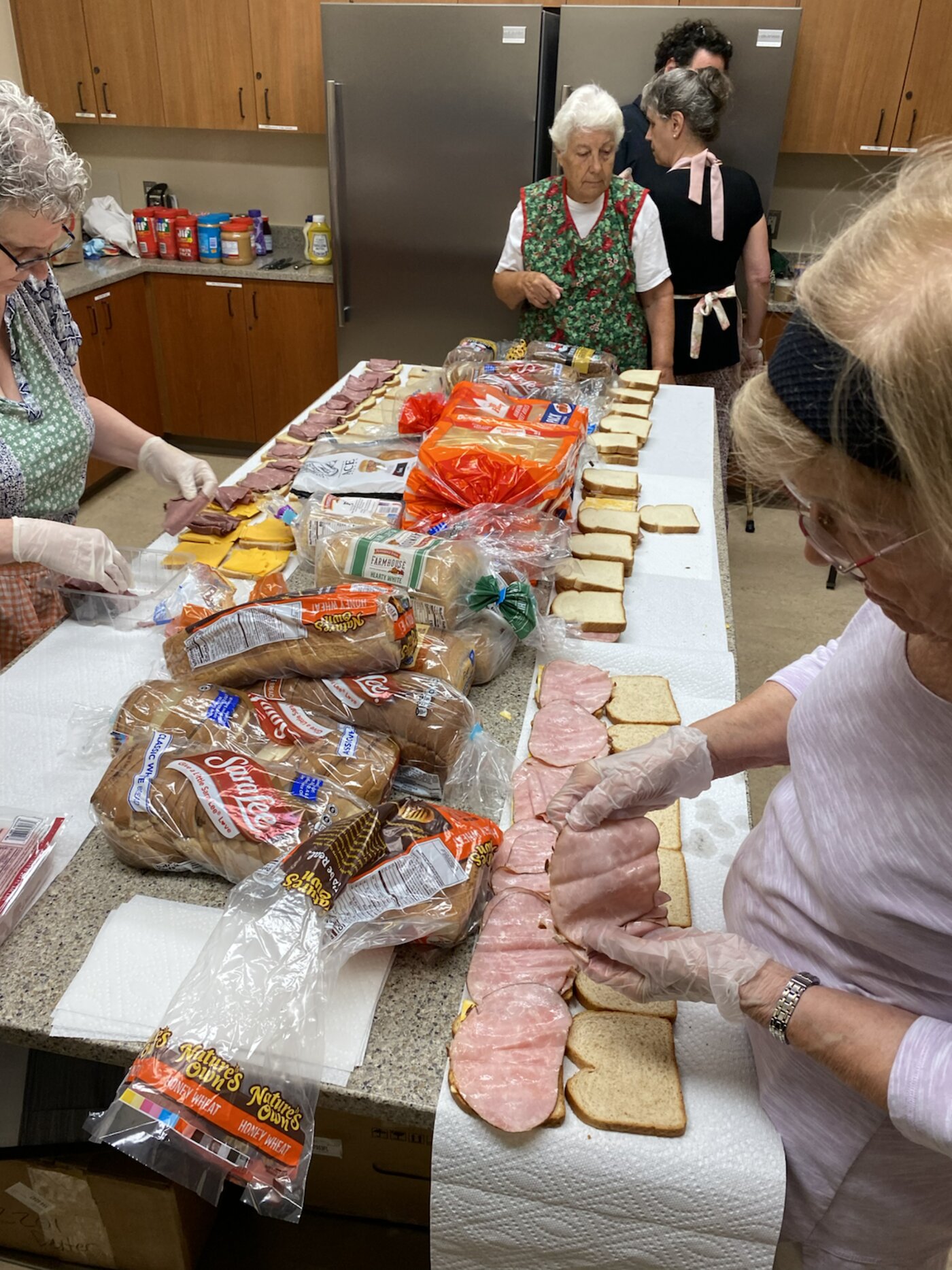 Volunteers in gloves making sandwiches from donated bread and lunch meat
