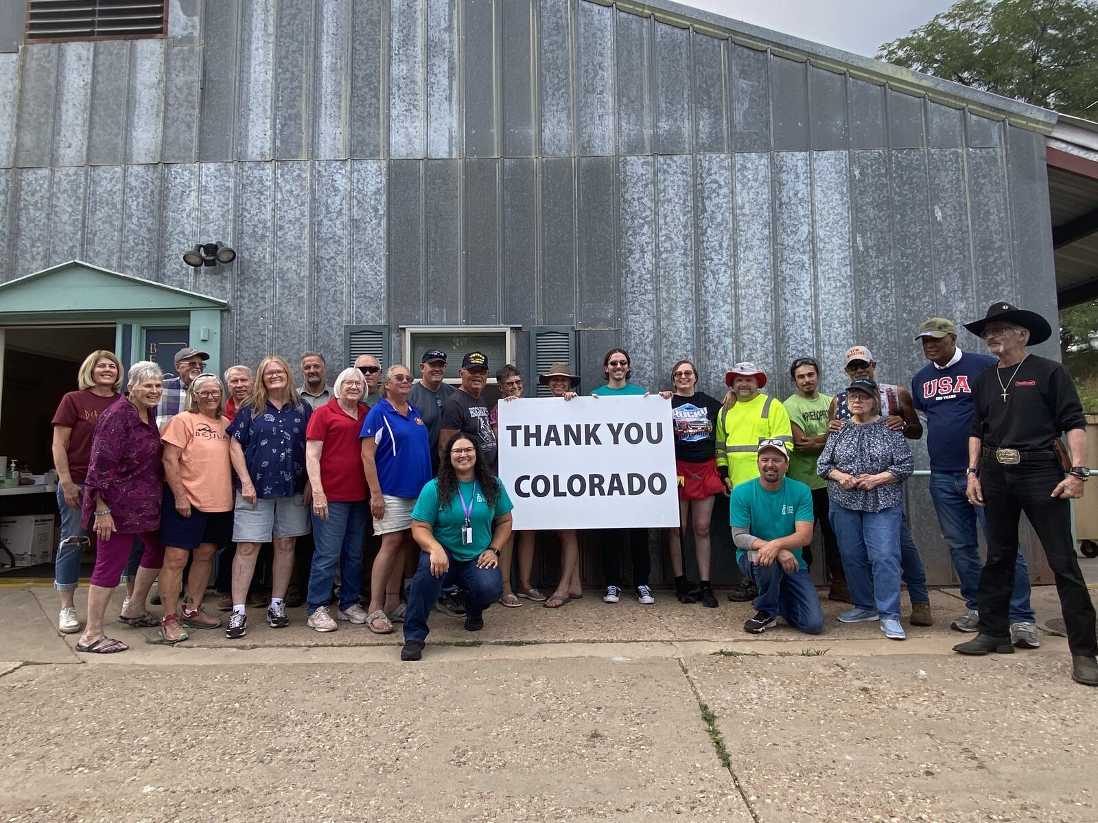 Beulah residents and volunteers gathered outside the community building holding a large Thank You Colorado sign