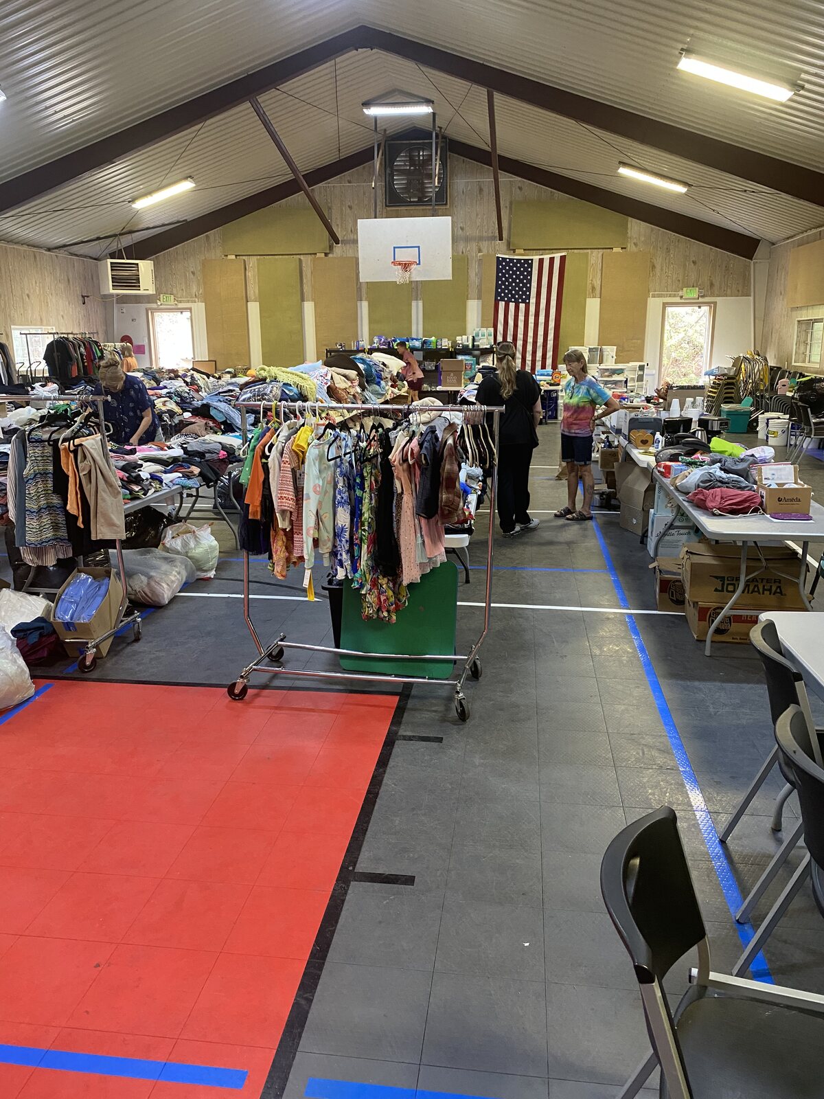 Racks and tables of donated clothing filling the community hall for families returning home