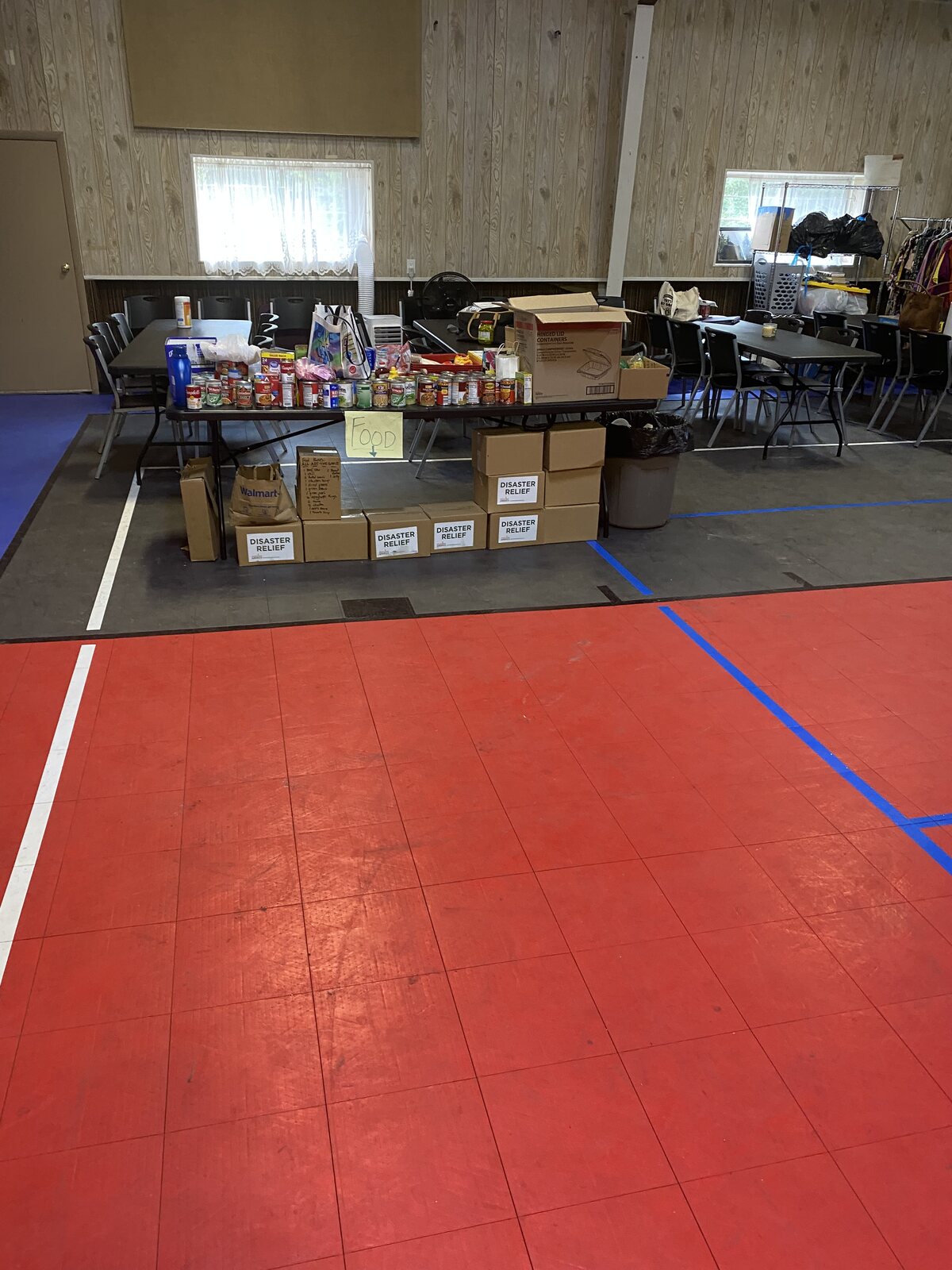 Tables of donated canned food and boxes marked Disaster Relief in the community hall