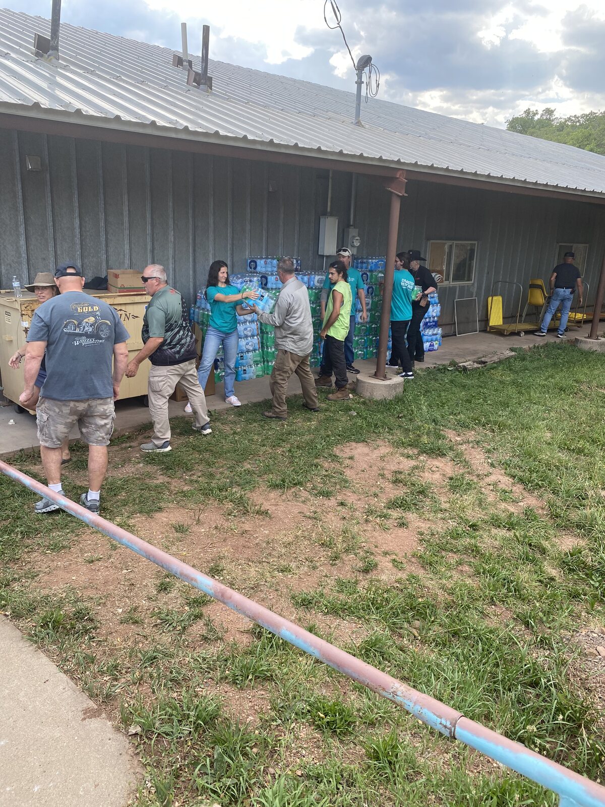 Volunteers unloading and stacking cases of donated drinking water outside the community building